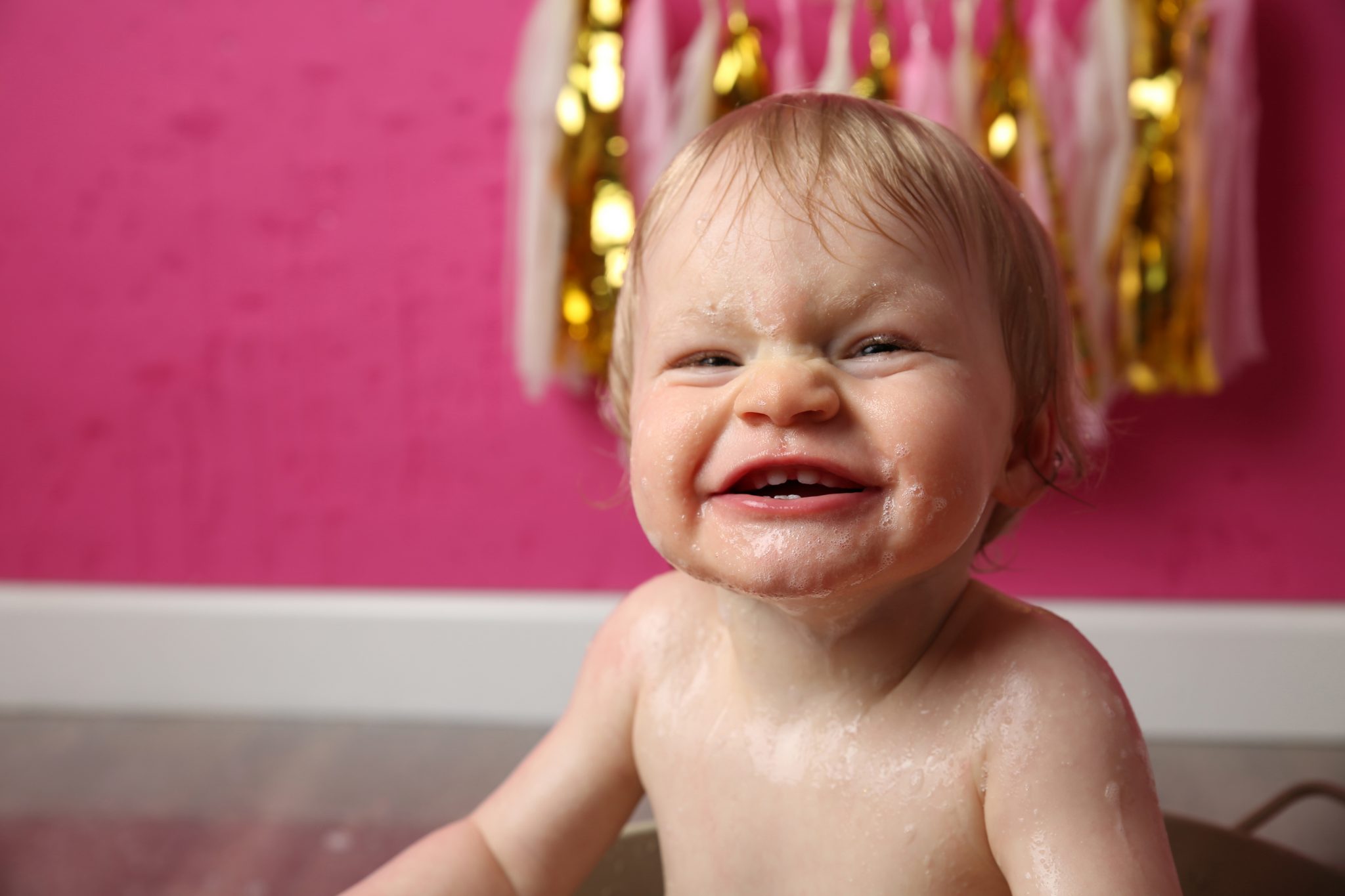 cheeky girl smiling at camera at cake smash photoshoot in east grinstead