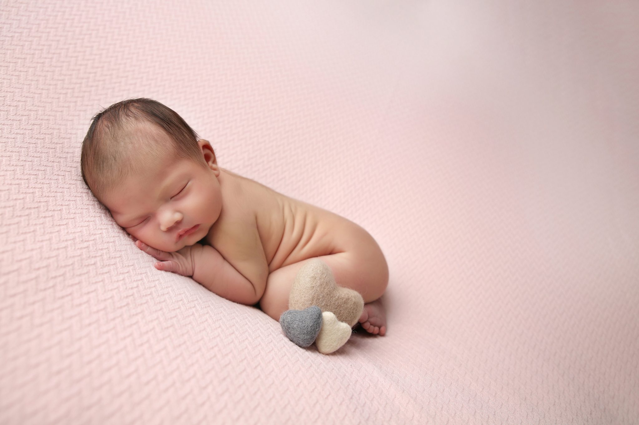 sleeping newborn baby on pink backdrop with heart props on photoshoot in west sussex