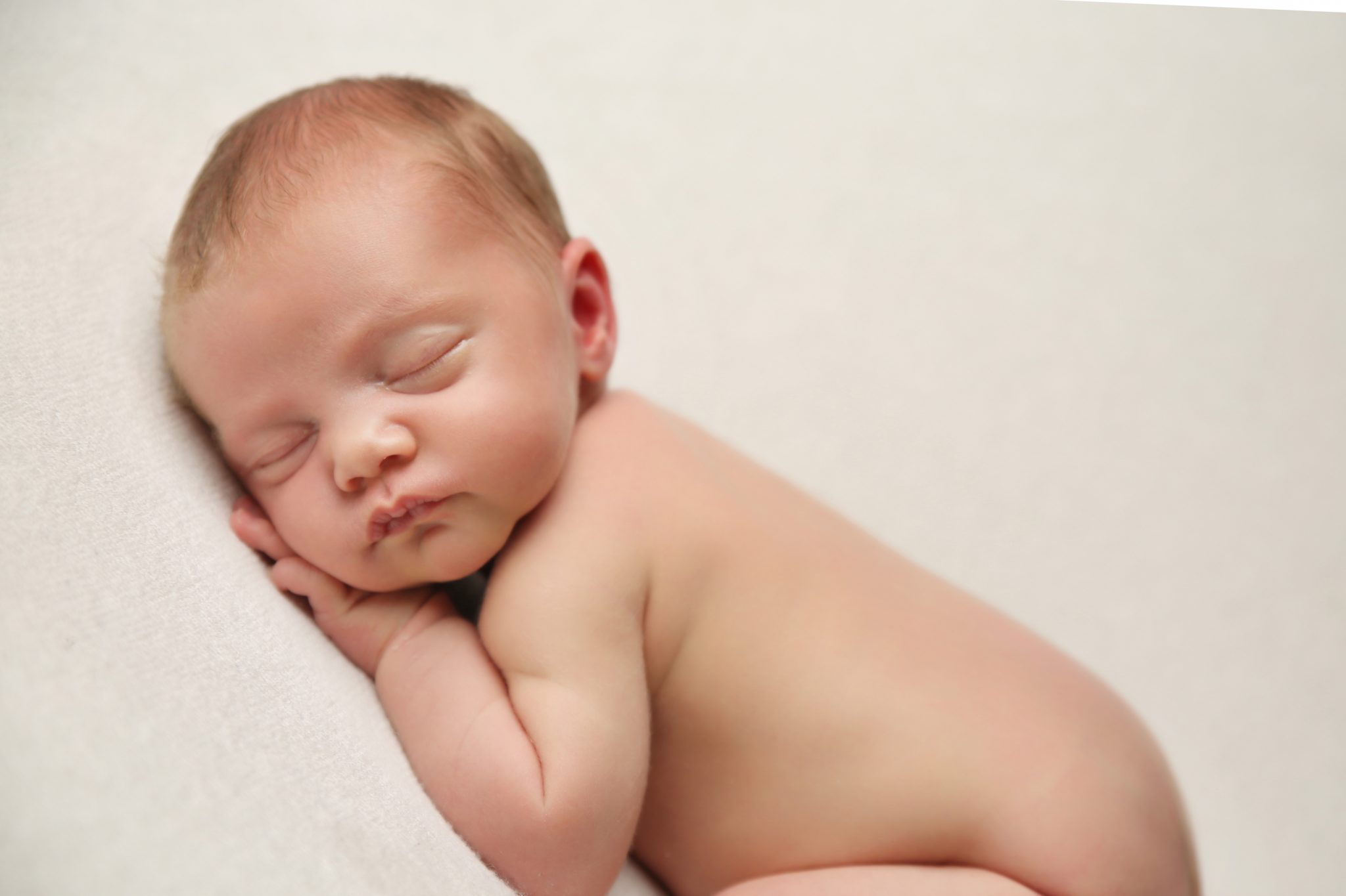 newborn baby asleep on white blanket natural image on photography session in west sussex